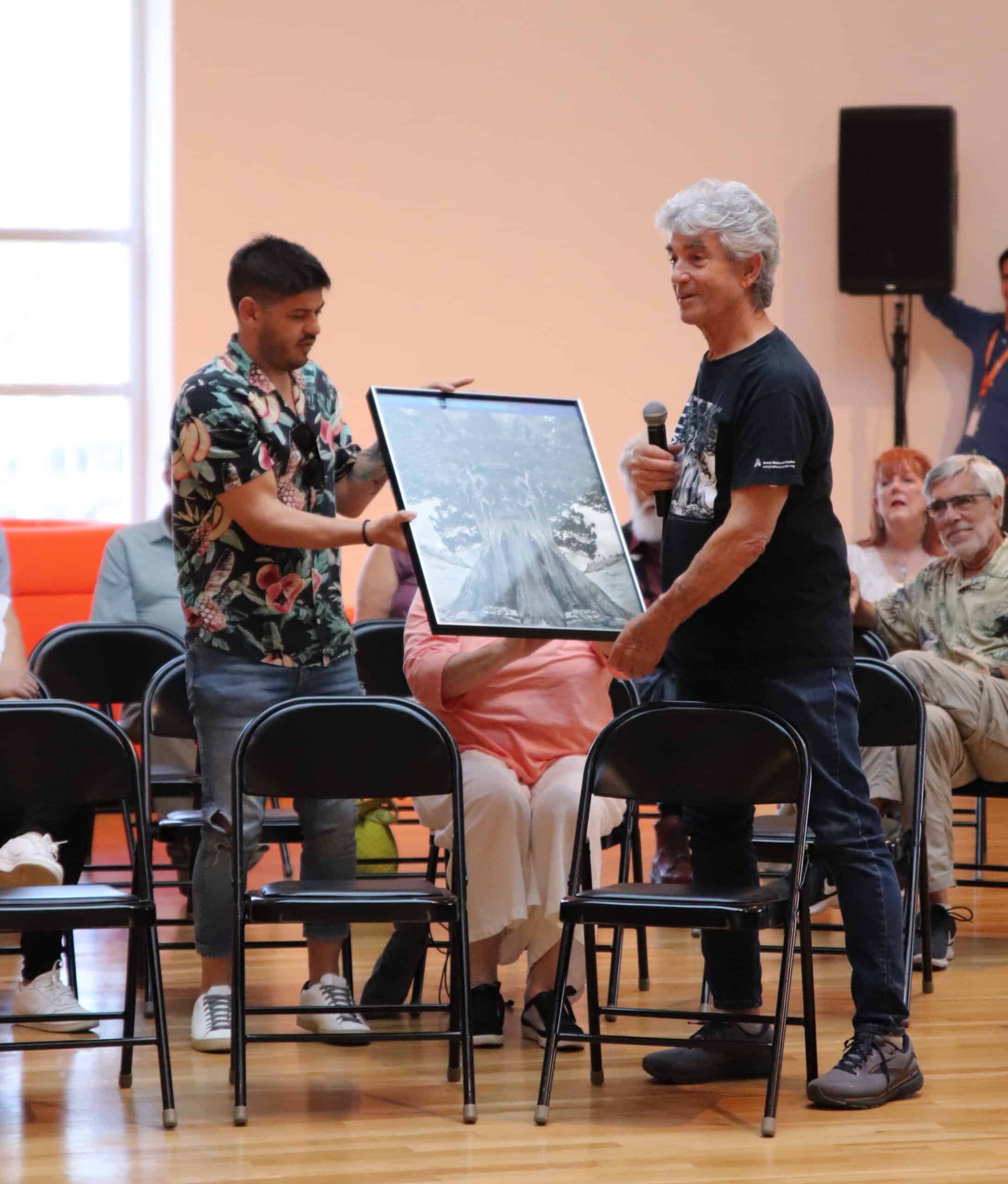 Photograph of colleagues of Jerry Uelsmann holding his artwork and discussing at an open forum in the museum Rotunda