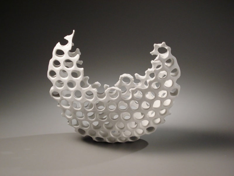 ceramic sculpture in a croissant-shaped sphere with dots poked throughout