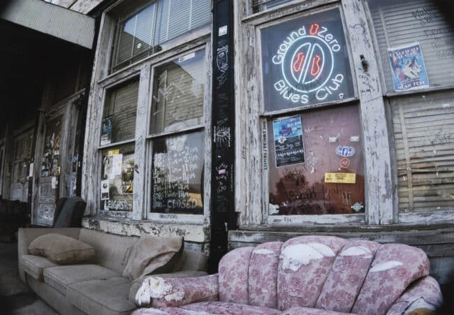 a photograph of outside of a Mississippi Blues club, with tattered couches in front of the building's windows