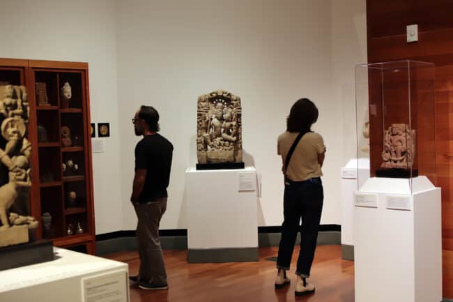 visitors in the Asian wing observing carvings and statues