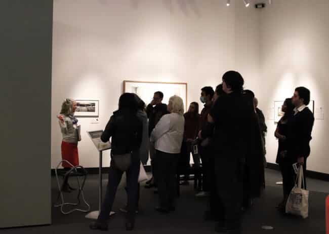 Harn docent gives a tour to a group of people in the photography gallery