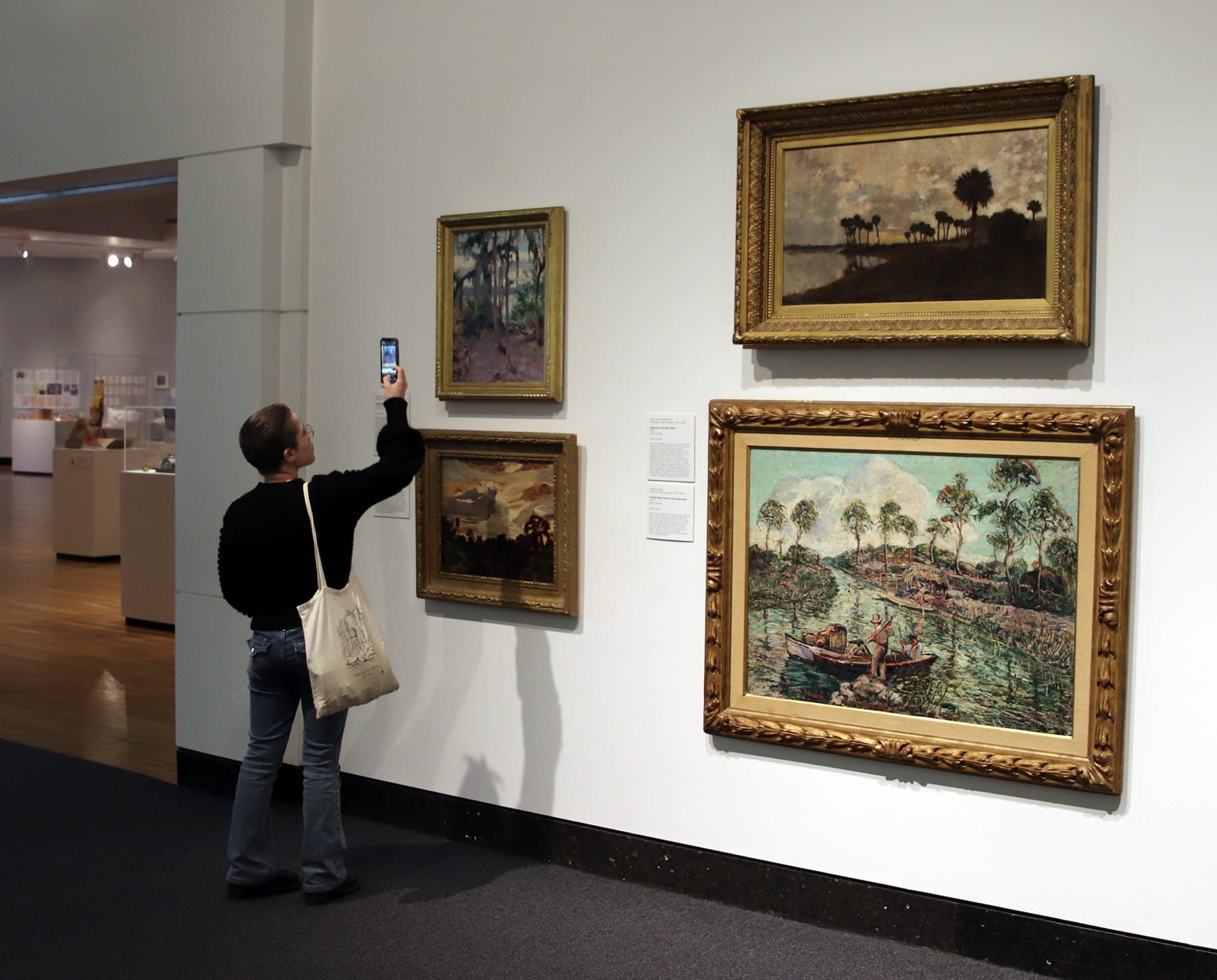 museum visitor taking a photo of a painting in the "Florida Impressions" exhibition