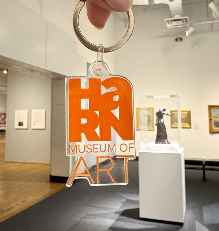photograph of a keychain with the Harn's logo in plastic, being held up in the modern gallery