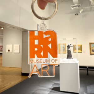 photograph of a keychain with the Harn's logo in plastic, being held up in the modern gallery
