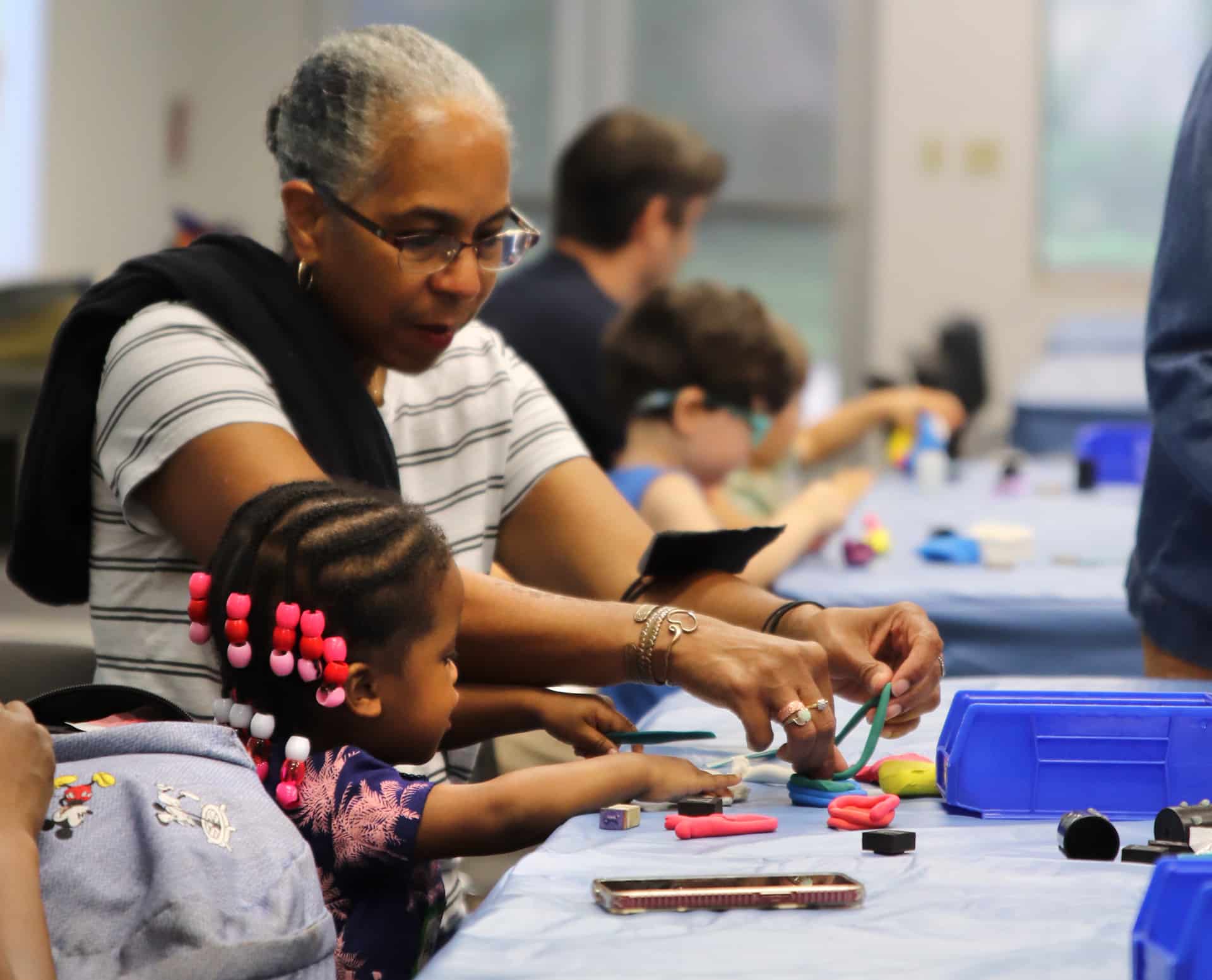 Young child and care giver molding with clay.