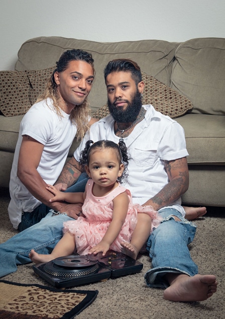Two adults and one child posing for a portrait in front of a couch