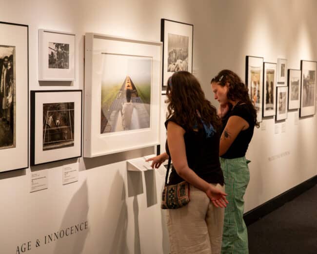Two people looking a wall of photographs in "One World" Exhibition