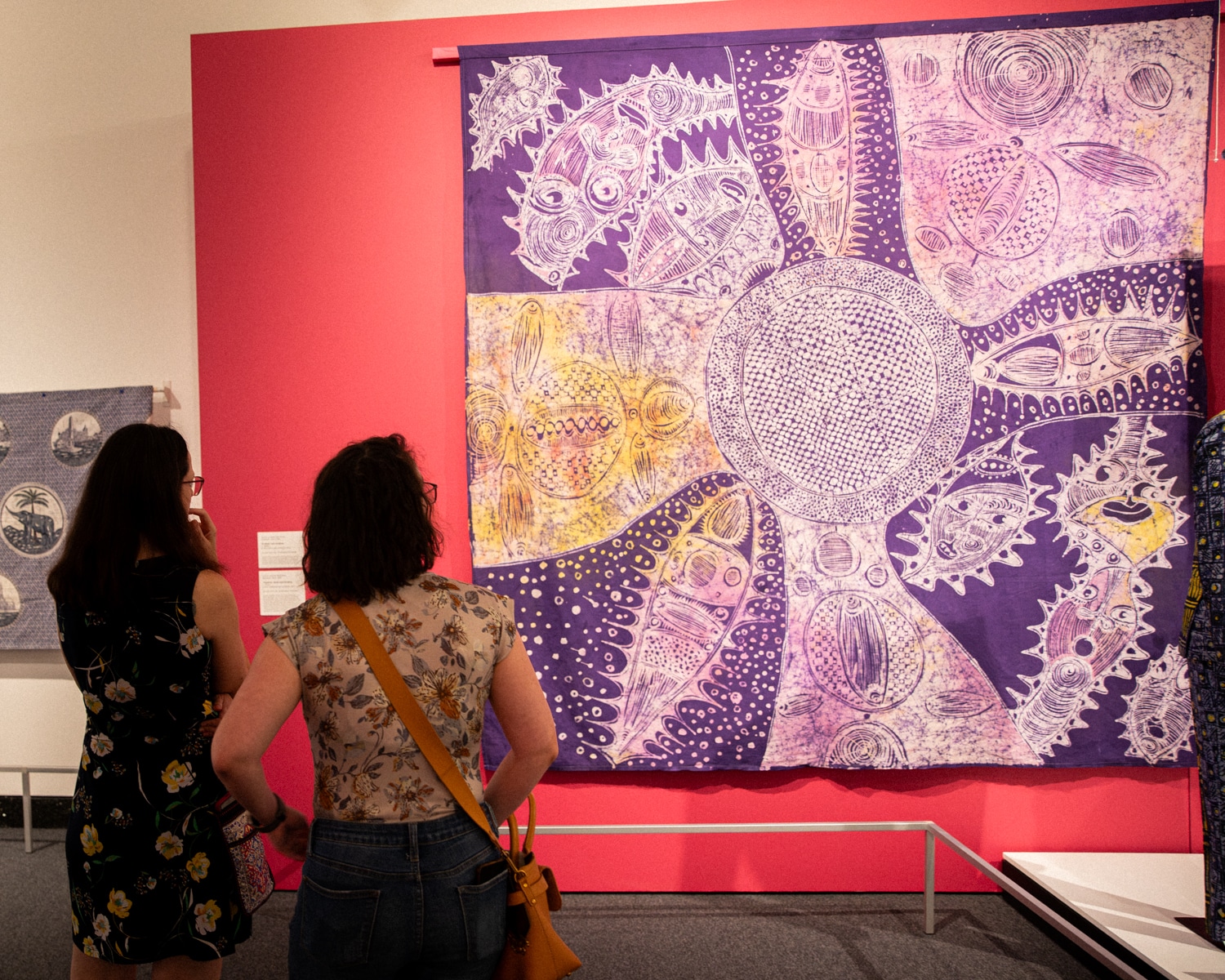 Two people standing by a large blue and white dyed Ghanaian cloth with an elaborate design.
